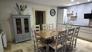 A dining area with a wooden table and chairs, a cabinet with glass doors, and a clock on the wall. - Peaceful charming house (Lapalud)