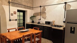 A kitchen with a wooden table and chairs, a refrigerator, a microwave, and a sink.