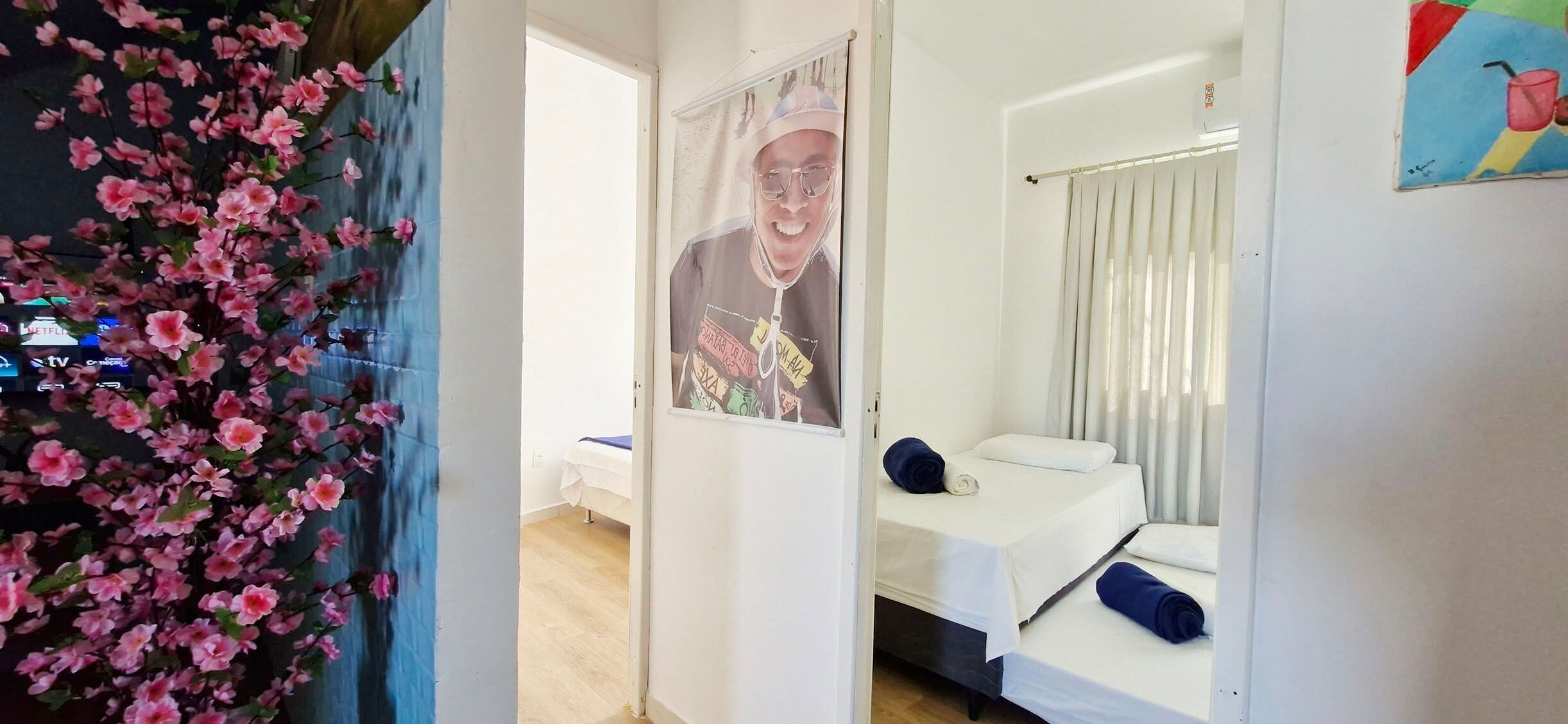 Habitación de hotel con cama, ventana con cortinas, un cartel en la pared y aire acondicionado instalado en la pared.