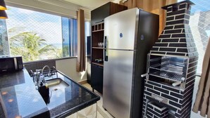 Eine Küche mit einem Edelstahl-Kühlschrank, einer schwarzen Arbeitsplatte, einem Spülbecken und einem Backofen aus Ziegelsteinen.