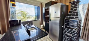 Eine Küche mit einem Edelstahl-Kühlschrank, einer schwarzen Arbeitsplatte, einem Spülbecken und einem Backofen aus Ziegelsteinen.