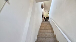 Eine Treppe führt zu einem Raum mit einer Pendelleuchte und einer Tür links.