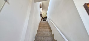 Eine Treppe führt zu einem Raum mit einer Pendelleuchte und einer Tür links.