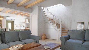 A modern living room with a wooden ceiling, grey sofas, a wooden coffee table, and a staircase leading to another room. - Village Escape House by CorfuEscapes (Corfu)