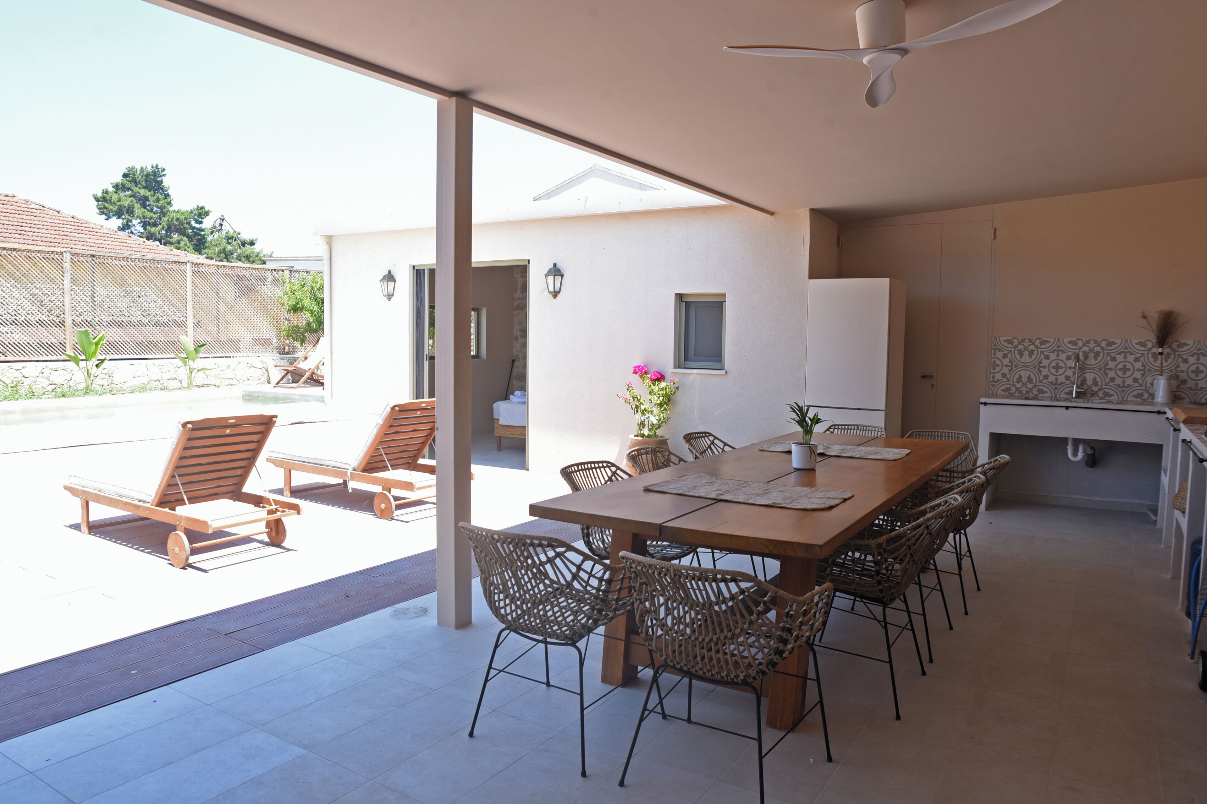 Un patio techado con una mesa de comedor, sillas y un ventilador de techo.