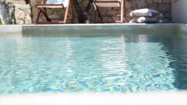 A clear pool with a stone wall and lounge chairs in the background. - Village Escape House by CorfuEscapes (Corfu)