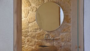 A stone wall, a round mirror, and a wooden basin. - Village Escape House by CorfuEscapes (Corfu)