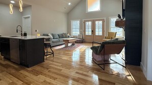 A spacious living area with a kitchen, a dining table, and a high ceiling with a fan. - 2 King beds! Sleep like royalty in this cozy, intimate, and brand-new house (Scottsville)