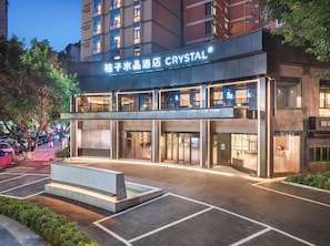 A hotel with a modern facade, multiple floors, and a prominent signage. - Orange Crystal Chongqing Guanyinqiao (Chongqing)