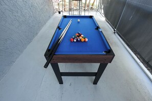 Una mesa de billar con superficie de fieltro azul, una bola blanca y una pirámide de bolas de billar.