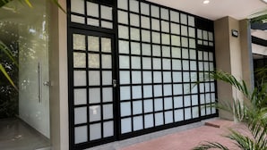 A building entrance with a glass door, a black-framed window with a grid pattern, and a number sign indicating the address. - Stay 32 (Medellín)