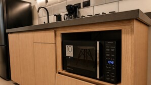 A kitchen with a built-in microwave, a coffee maker, and a digital clock displaying the time. - Stay 32 (Medellín)