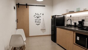 A modern kitchen with a black refrigerator, a coffee maker, and a wall-mounted sign. - Stay 32 (Medellín)