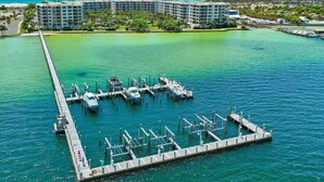 A marina with boats docked, a pier extending into the water, and a hotel complex in the background. - Destin West Bayside Sandpiper #405 (Fort Walton Beach)