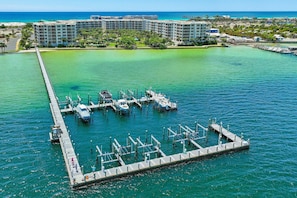 Ein Yachthafen mit vertäuten Booten, eine Mole, die ins Wasser führt, und ein Hotelkomplex im Hintergrund.