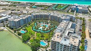 A resort with multiple buildings, a central pool area, and a beach view. - Destin West Bayside Sandpiper #405 (Fort Walton Beach)