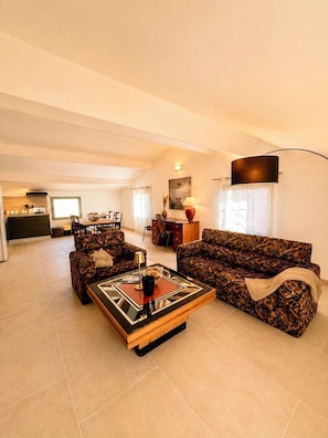 A living room with a sofa, coffee table, and a dining area with chairs and a table. - Résidence ANTONIA - Attic apartment with pool access - Calvi town center (Calvi)