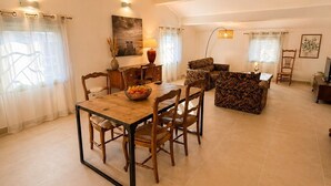 Un vaste espace de vie comprenant une table à manger, des chaises, un canapé à motifs et un téléviseur.