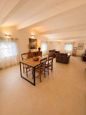 A spacious living area with a dining table, chairs, a patterned sofa, and a television. - Résidence ANTONIA - Attic apartment with pool access - Calvi town center (Calvi)
