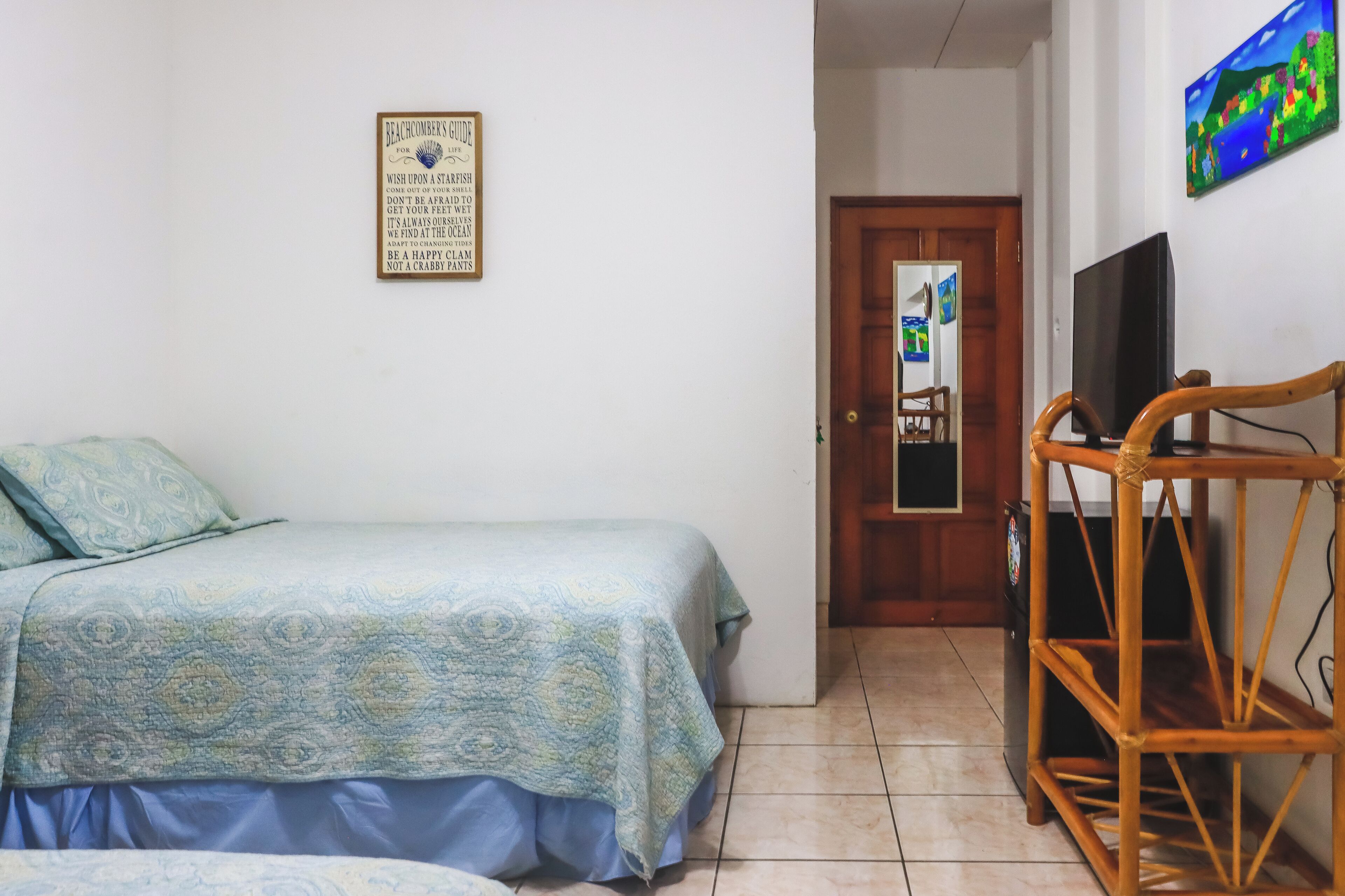 Ein Schlafzimmer mit einem Bett, einem Holzstuhl, einem Fernseher und einer Tür.