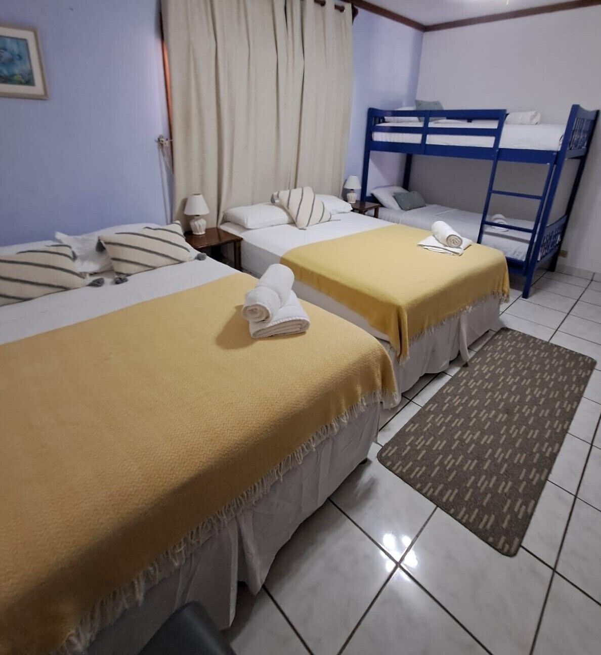 Una habitación con dos camas, incluida una litera, un tapete estampado y un cuadro en la pared.