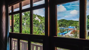 A view through a window with a wooden frame, a white building with a dome, and a green landscape. - Hotel Gracia (San Juan del Sur)
