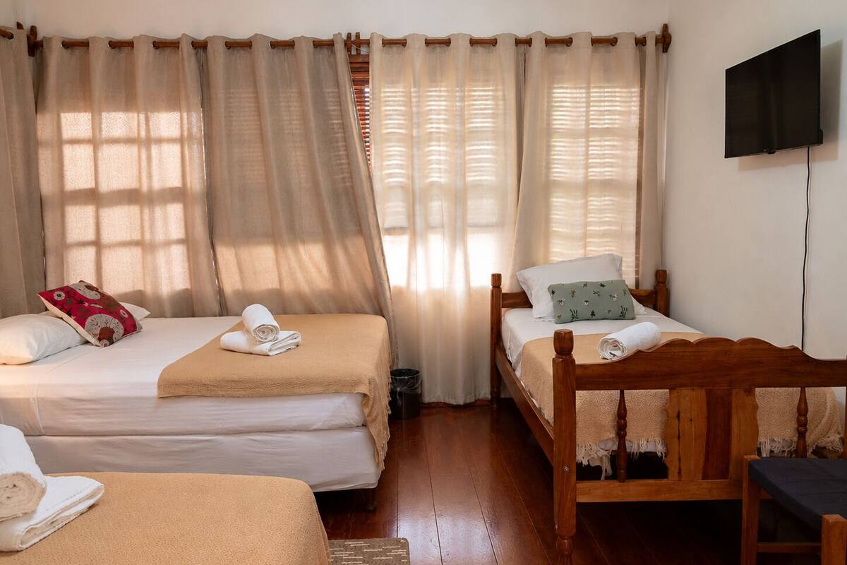 Une chambre avec deux lits, une télévision et une chaise en bois.