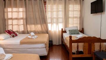 A room with two beds, a TV, and a wooden chair.