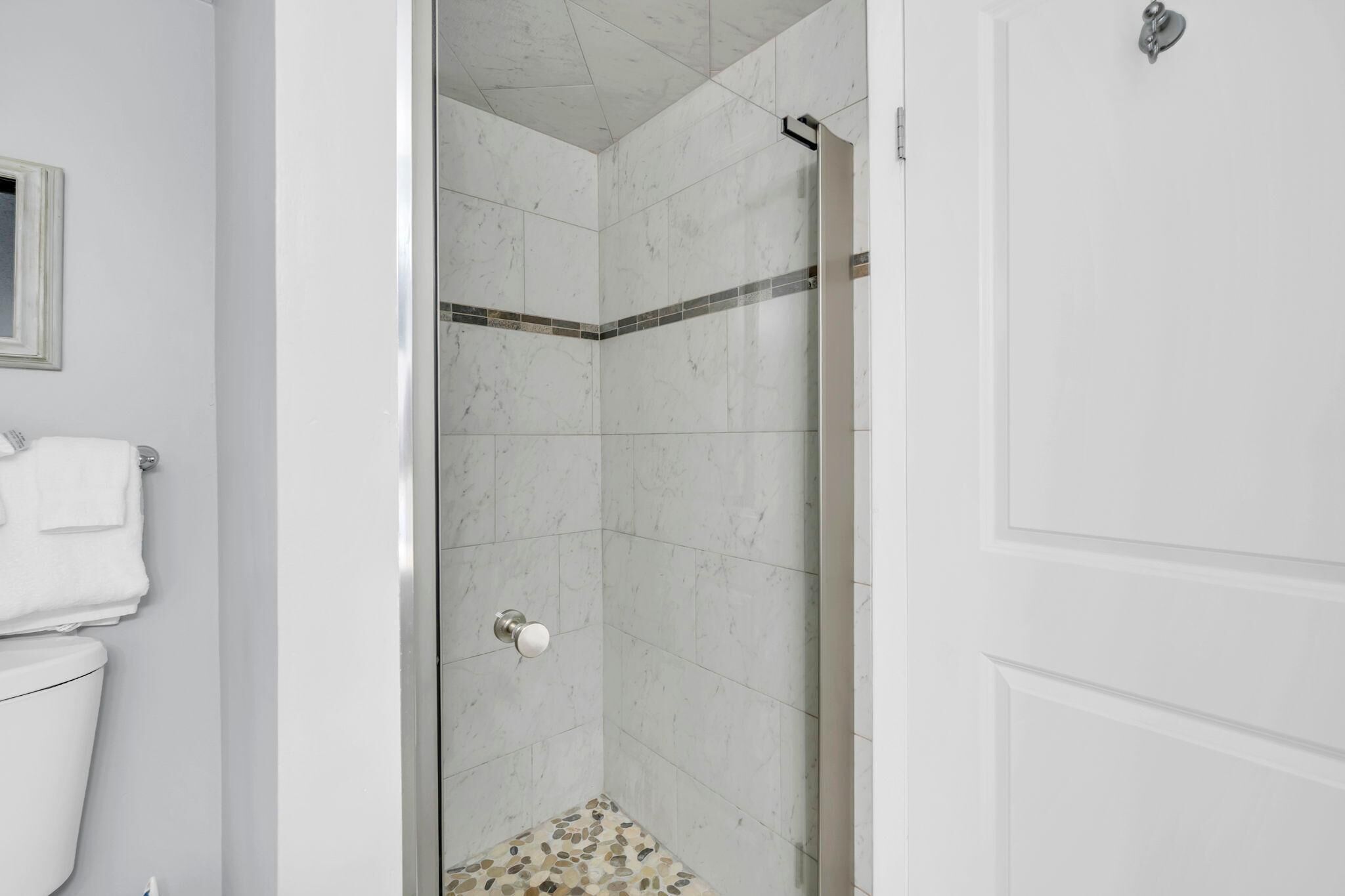 A bathroom with a shower, toilet, and a towel rack.