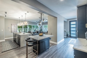 A modern kitchen with a large island, pendant lighting, and a view to the outdoors. - Massage Chairs, Foosball, Wet Bar & Board Games (Roanoke)
