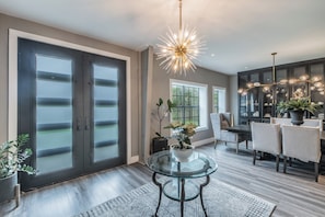 A modern interior with a glass table, dark doors, and a decorative light fixture. - Massage Chairs, Foosball, Wet Bar & Board Games (Roanoke)