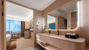 A modern hotel room with a large bed, a sitting area, a vanity with a mirror, and a view of the city. - Chongqing Jinkai Aegean Crystal HoteL (Chongqing)