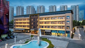 A hotel with a modern design, multiple floors, and a central courtyard with a fountain. - Chongqing Jinkai Aegean Crystal HoteL (Chongqing)
