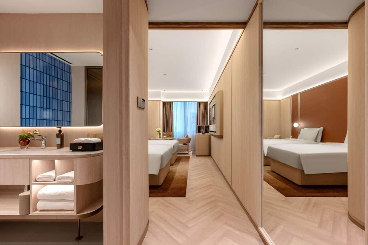 A hotel room with a modern design, a separate bathroom, a small sitting area, and a view of the city.