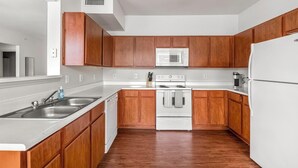 A modern kitchen with wooden cabinets, a stainless steel sink, a microwave, an oven, and a refrigerator.