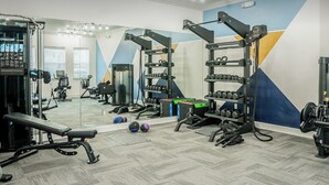 A gym with exercise equipment, a bench, and a mirror.