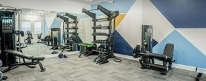 A gym with exercise equipment, a bench, and a mirror.