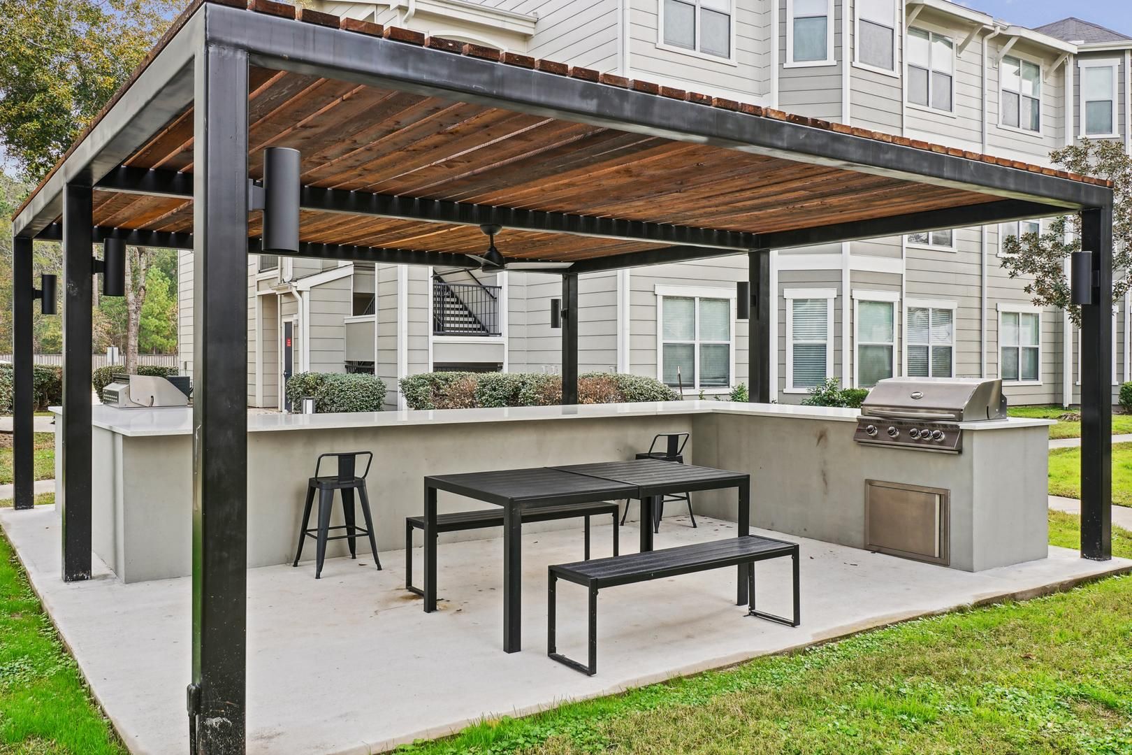 Eine Terrassengaststätte mit Grill, Sitzgelegenheiten und einer Pergola.