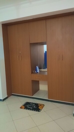 A room with a large wooden wardrobe, a small mirror, and a tiled floor. - Welcoming 1-bedroom apartment in vibrant Mombasa perfect for relaxing (Mombasa)