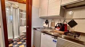 Een kleine keuken met een spoelbak, een compacte koelkast en een gasfornuis.