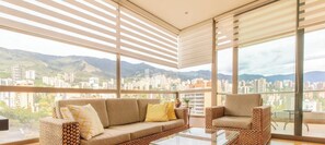 A modern living room with a sofa and chairs, large windows, and a cityscape view. - Luxury 3 Bedroom Apartment in Provence (Medellín)