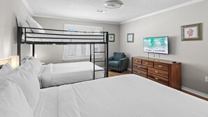 A bedroom with bunk beds, a television, a dresser, and a chair. - Bamba's Beach House (Destin)