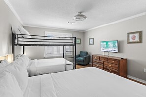 A bedroom with bunk beds, a television, a dresser, and a chair. - Bamba's Beach House (Destin)