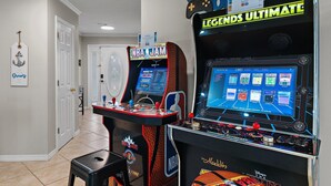 Two arcade machines, a door, and a wall sign. - Bamba's Beach House (Destin)