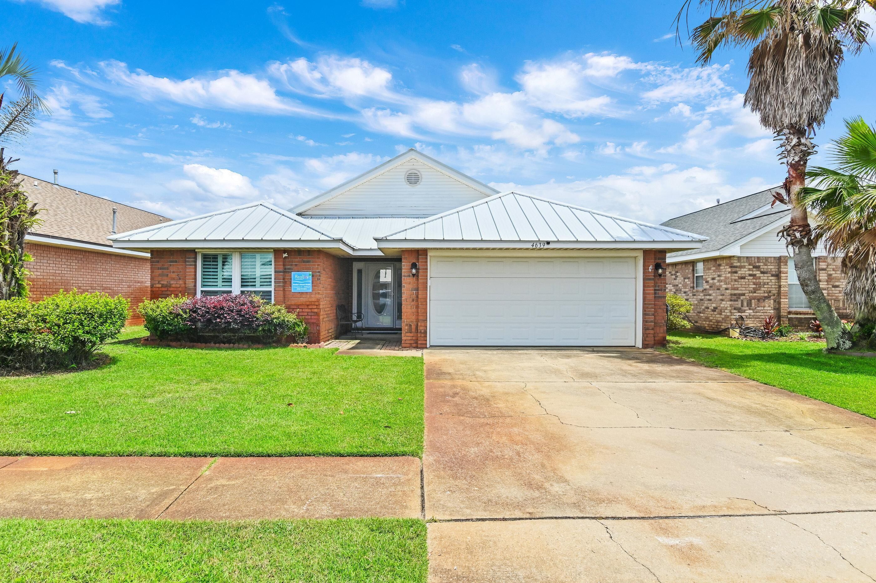 A single-story house with a garage, a front lawn, and a palm tree.