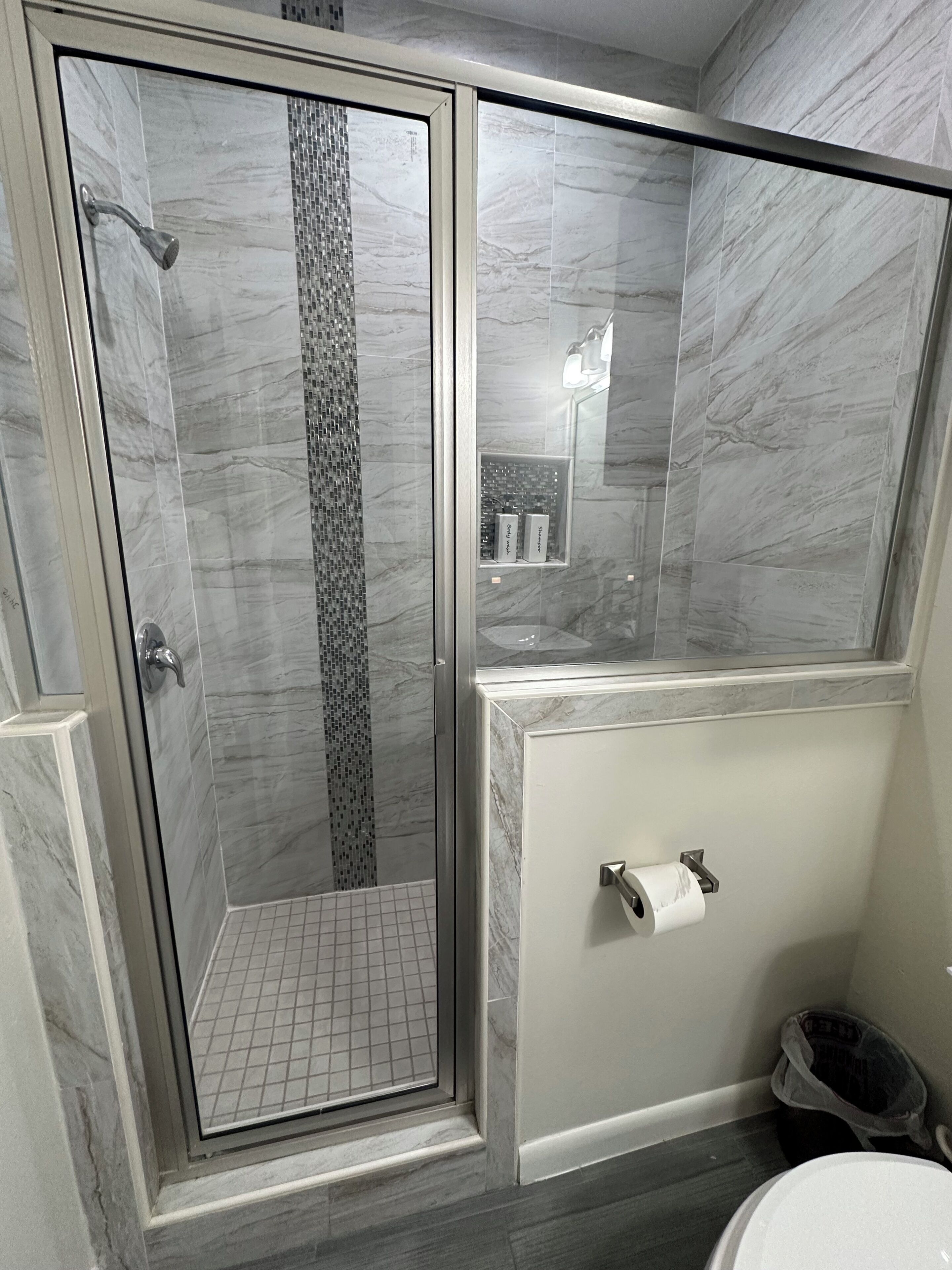 A bathroom with a glass-enclosed shower, a toilet, and a sink.