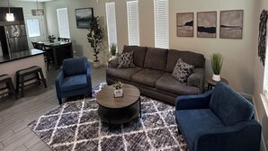 A modern living room with a sectional sofa, two armchairs, a coffee table, and a ceiling fan. - Beautiful Apartment with 4 Beds in Gated Community Close of Shops (McAllen)