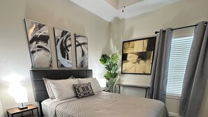 A bedroom with a bed, nightstand, wall art, ceiling fan, and window with curtains. - Beautiful Apartment with 4 Beds in Gated Community Close of Shops (McAllen)