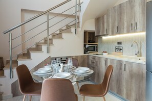 Una cuina moderna amb microones integrat, taula de dinar preparada per a quatre persones i escala amb barana metàl·lica.