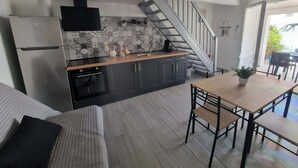 A modern kitchen with a built-in oven, a dining area with a wooden table and chairs, and a staircase leading to another level.
